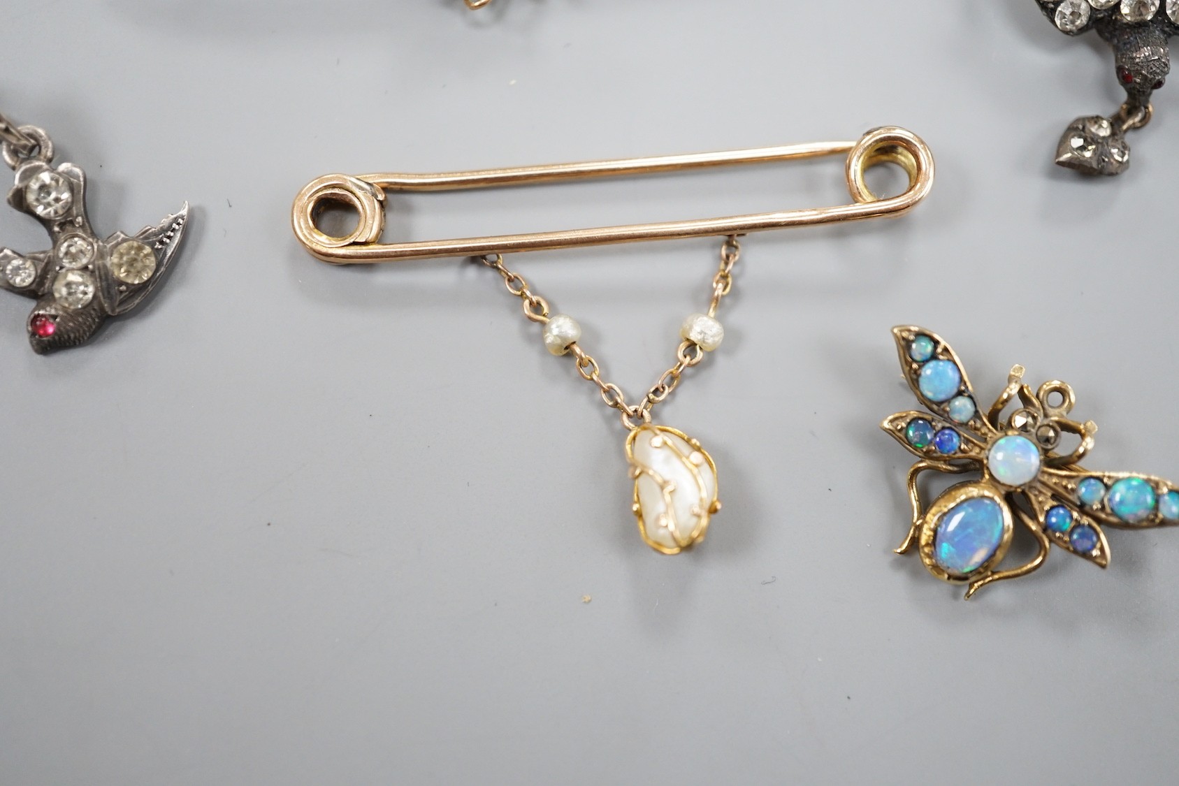 A modern 9ct gold and opal set bug brooch, 24mm, a paste set white metal swallow pendant and similar brooch and two yellow metal bar brooches, one with gem set spider, the other with baroque pearl drop.